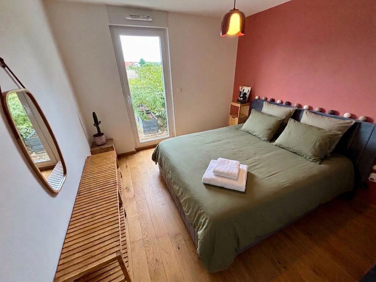 Une chambre à coucher avec un lit, une table de chevet, un miroir et une fenêtre.