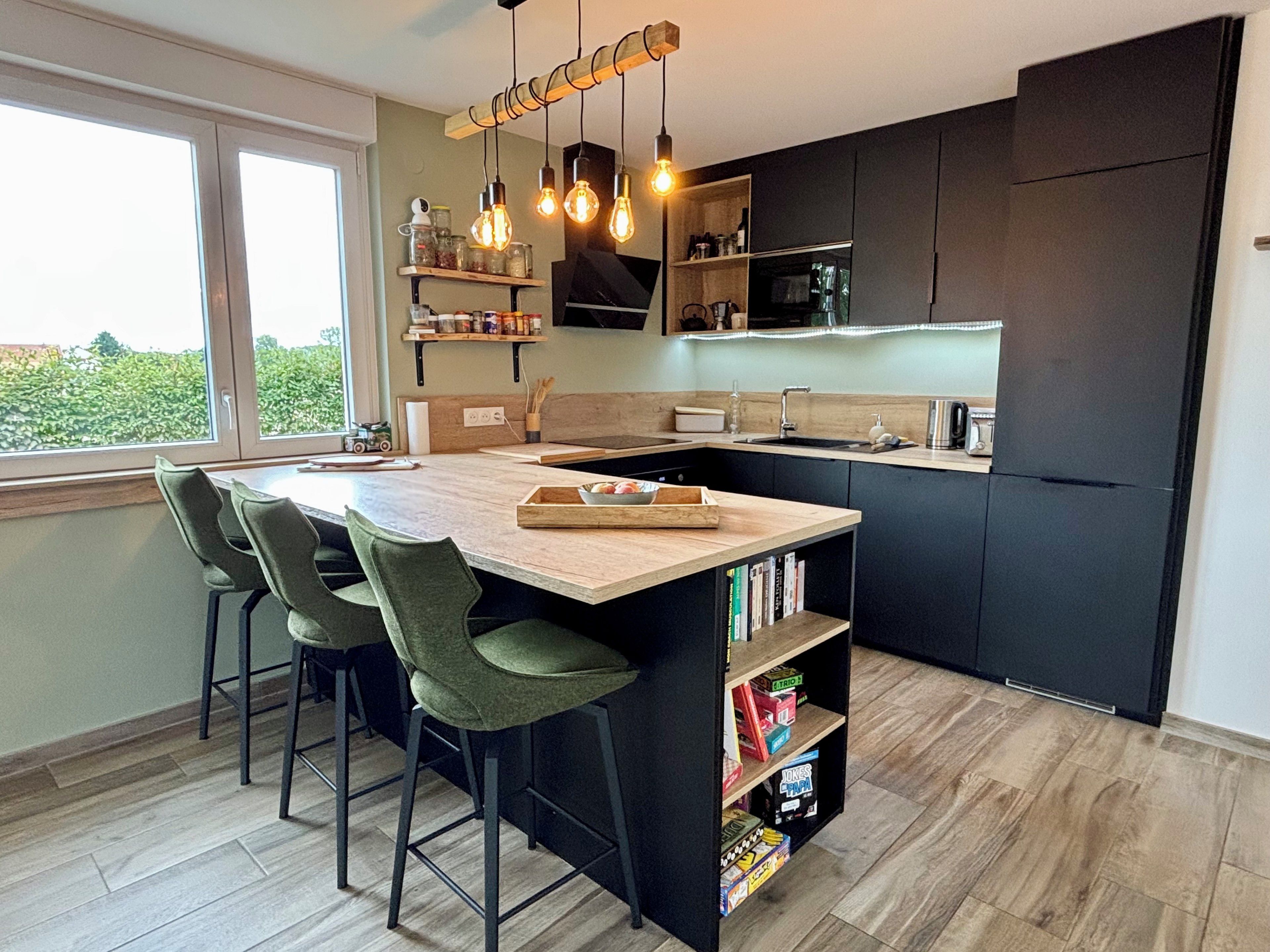 Une cuisine moderne dotée d’un îlot central, de tabourets de bar, d’étagères intégrées et offrant une vue par une fenêtre.