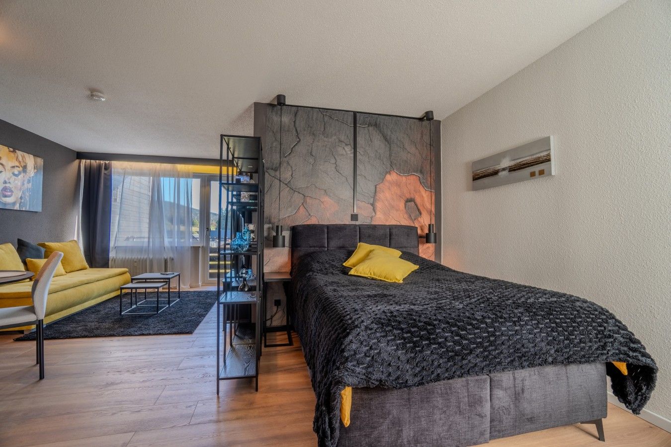 Een moderne slaapkamer met een groot bed, een bank, een bureau en uitzicht op de stad.