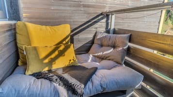 Una terraza de madera con zona de estar acolchada y varios cojines.