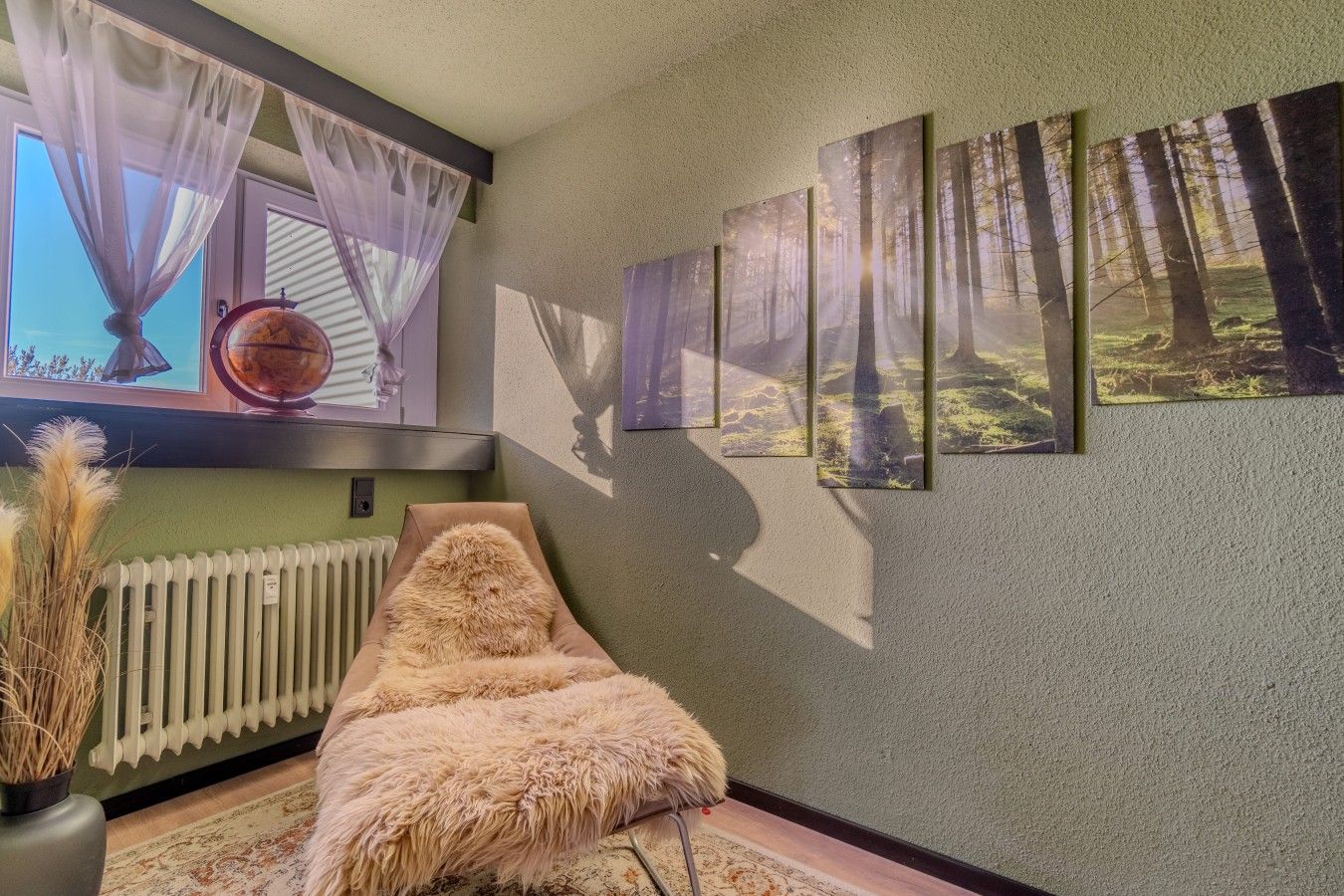 A room with a radiator, a fur-covered chair, and a series of forest-themed wall art.