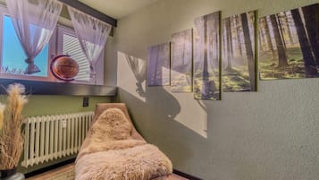 A room with a radiator, a fur-covered chair, and a series of forest-themed wall art.