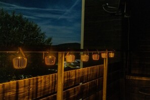 A wooden deck with a railing, decorated with string lights.