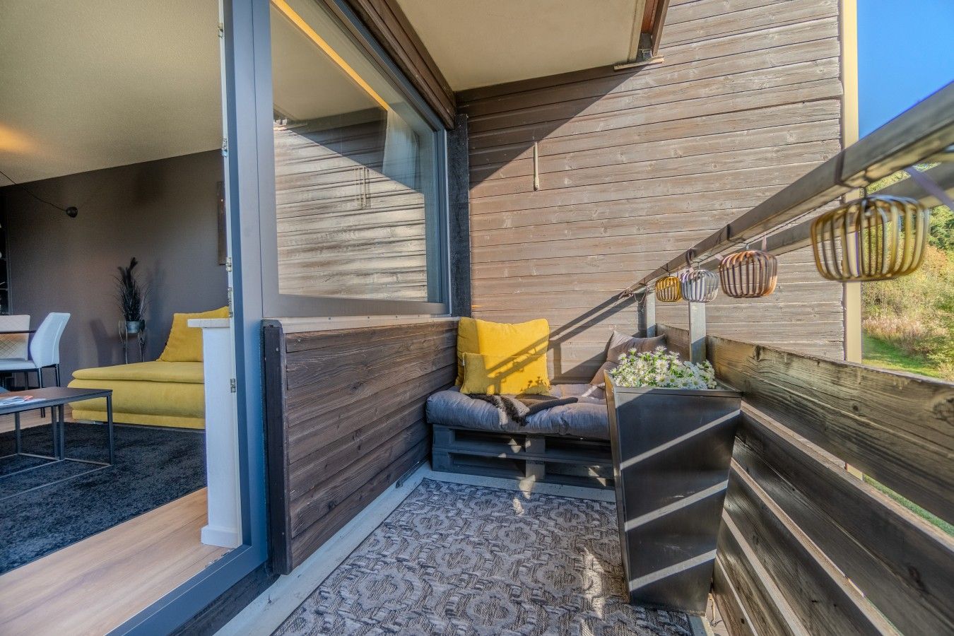 Un intérieur moderne avec un canapé, un coin repas et une terrasse en bois.