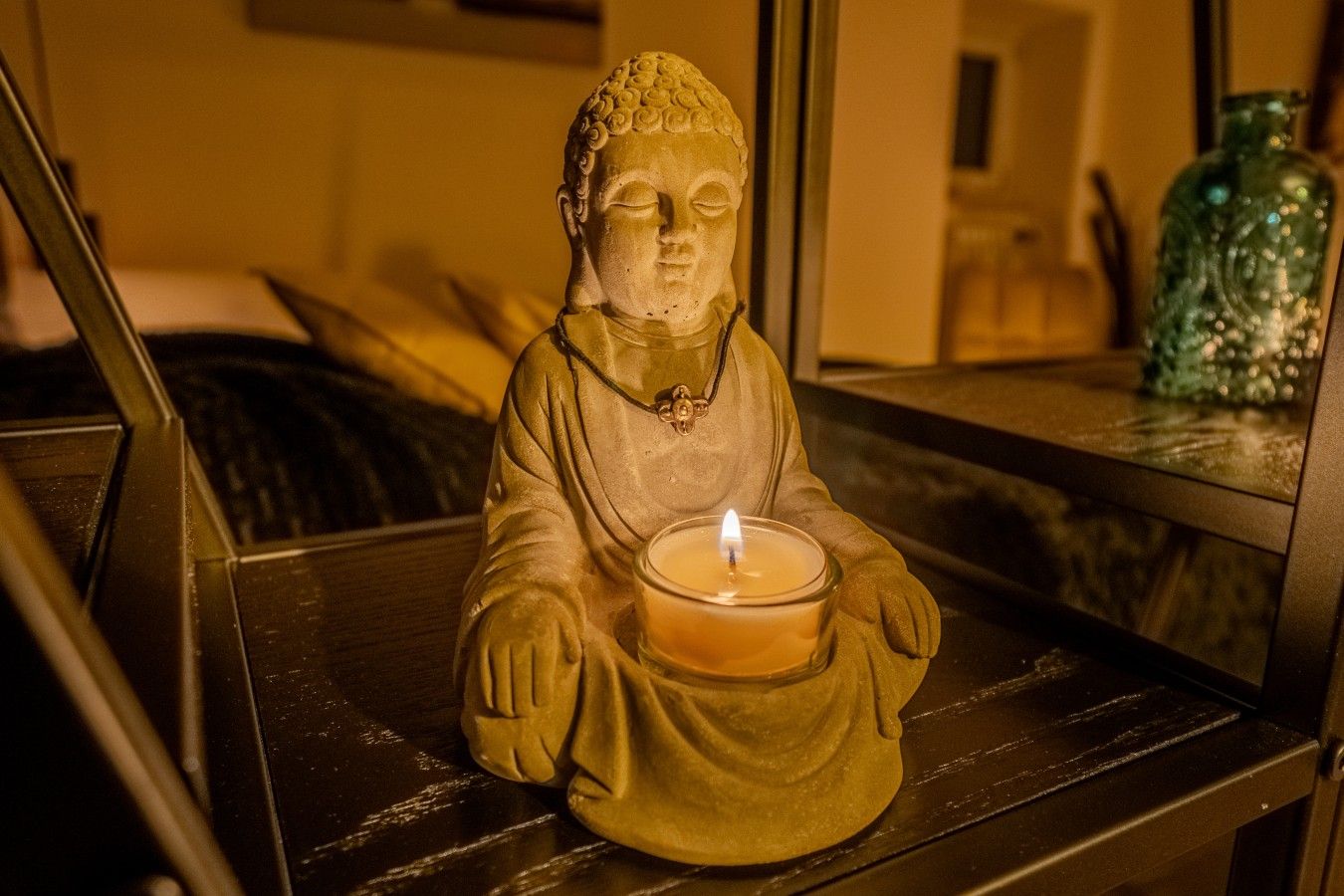 A statue of a seated figure holding a candle on a shelf.