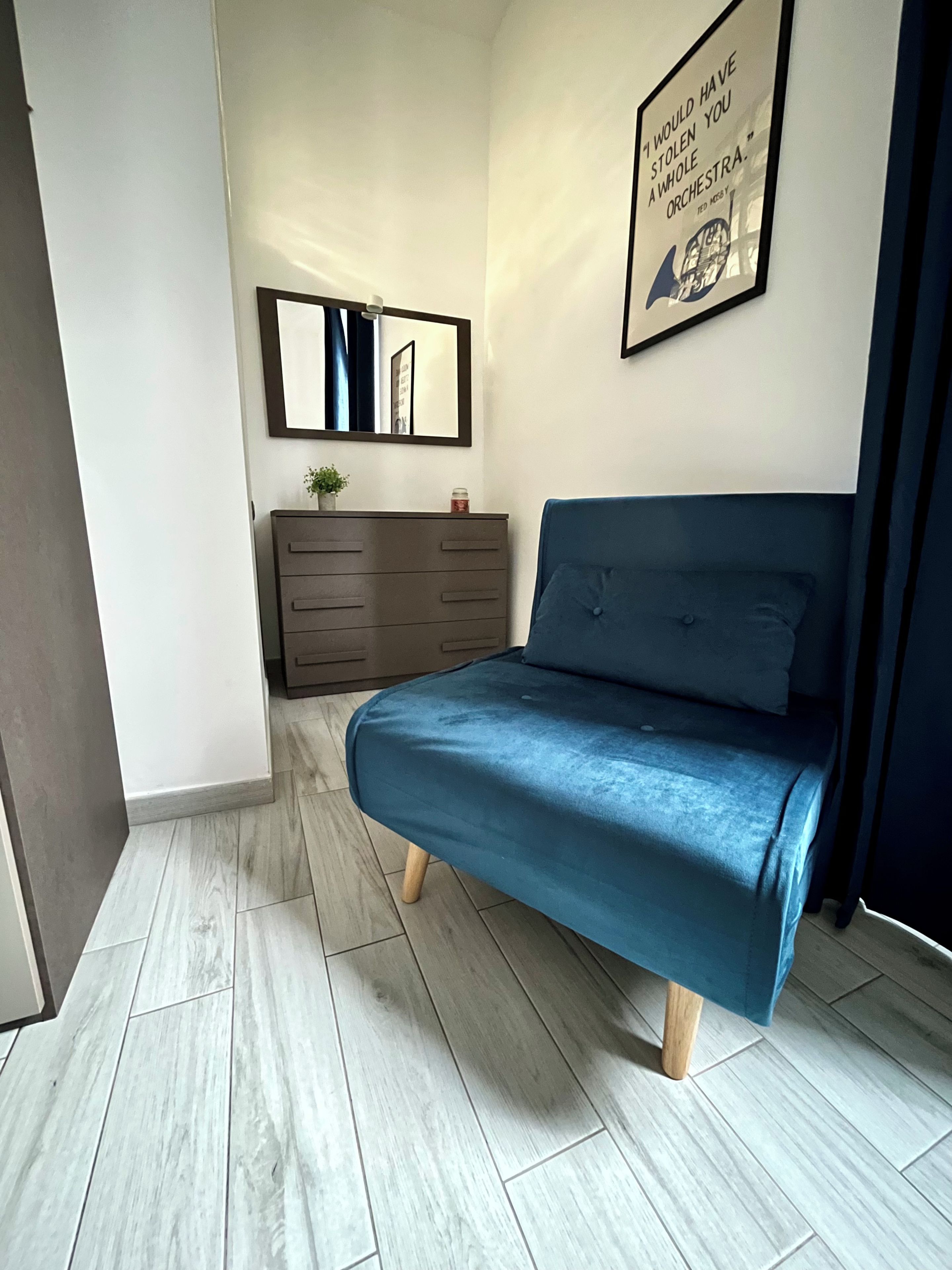 Una camera da letto con un letto, una cassettiera, uno specchio e una citazione incorniciata al muro.