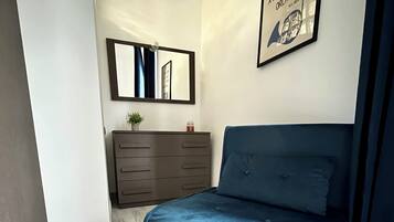 Una camera da letto con un letto, una cassettiera, uno specchio e una citazione incorniciata al muro.