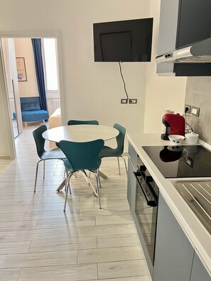 A modern kitchen with a white countertop, a built-in oven, and a wall-mounted television. - Casa Penelope - Nolo - M1 Rovereto - 15 minutes from the Duomo (Milano)