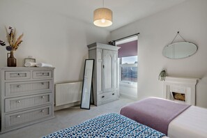 A bedroom with a bed, dresser, mirror, and a view of the outside. - Host & Stay | Indigo Snug (Cromer)