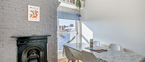 A dining area with a table, chairs, and a fireplace.