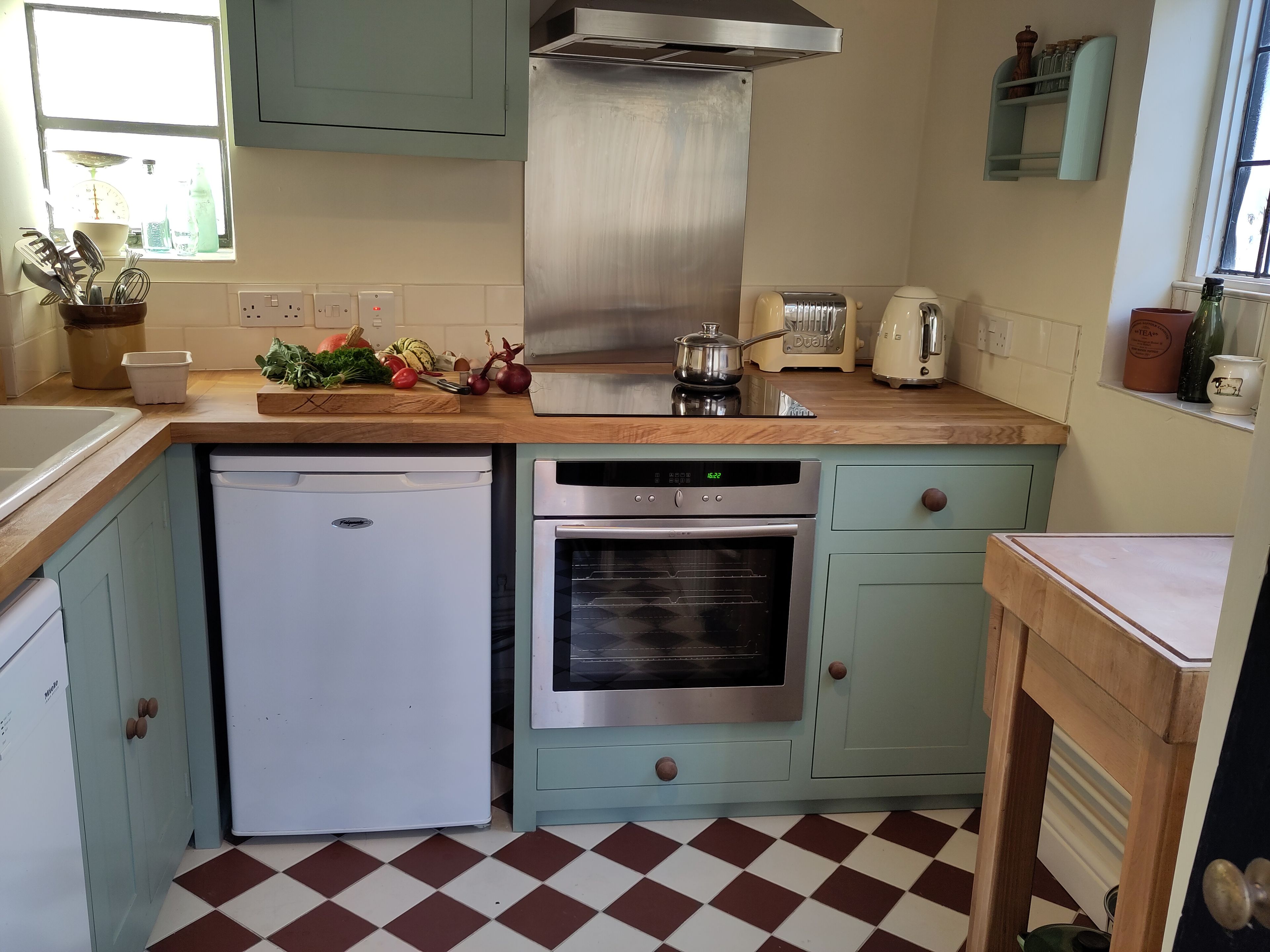 A kitchen with a dishwasher, oven, and a window with a view.