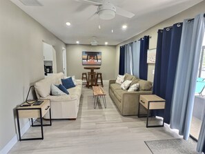 A modern living room with two sofas, a coffee table, and a ceiling fan. - Amazing Canal Home, Heated Pool, Spa & Fishing (Cape Coral)