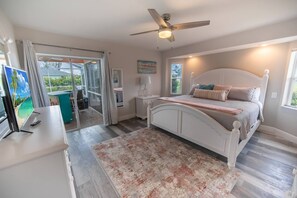 Ein Schlafzimmer mit einem Bett, einem Schreibtisch, einem Deckenventilator und Blick ins Freie.