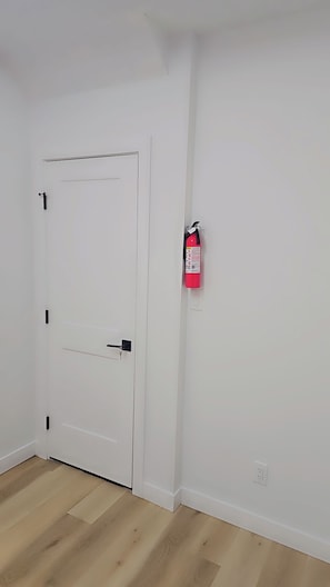 A white door with a fire extinguisher mounted on the wall beside it. - Modern, Clean and cozy suite (Edmonton)