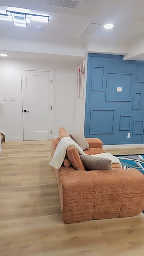 A room with a brown sofa, a white door, and a blue accent wall. - Modern, Clean and cozy suite (Edmonton)