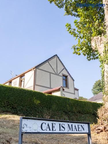 Ein Haus mit einem Schild, auf dem 'CAE IS MAEN' steht.