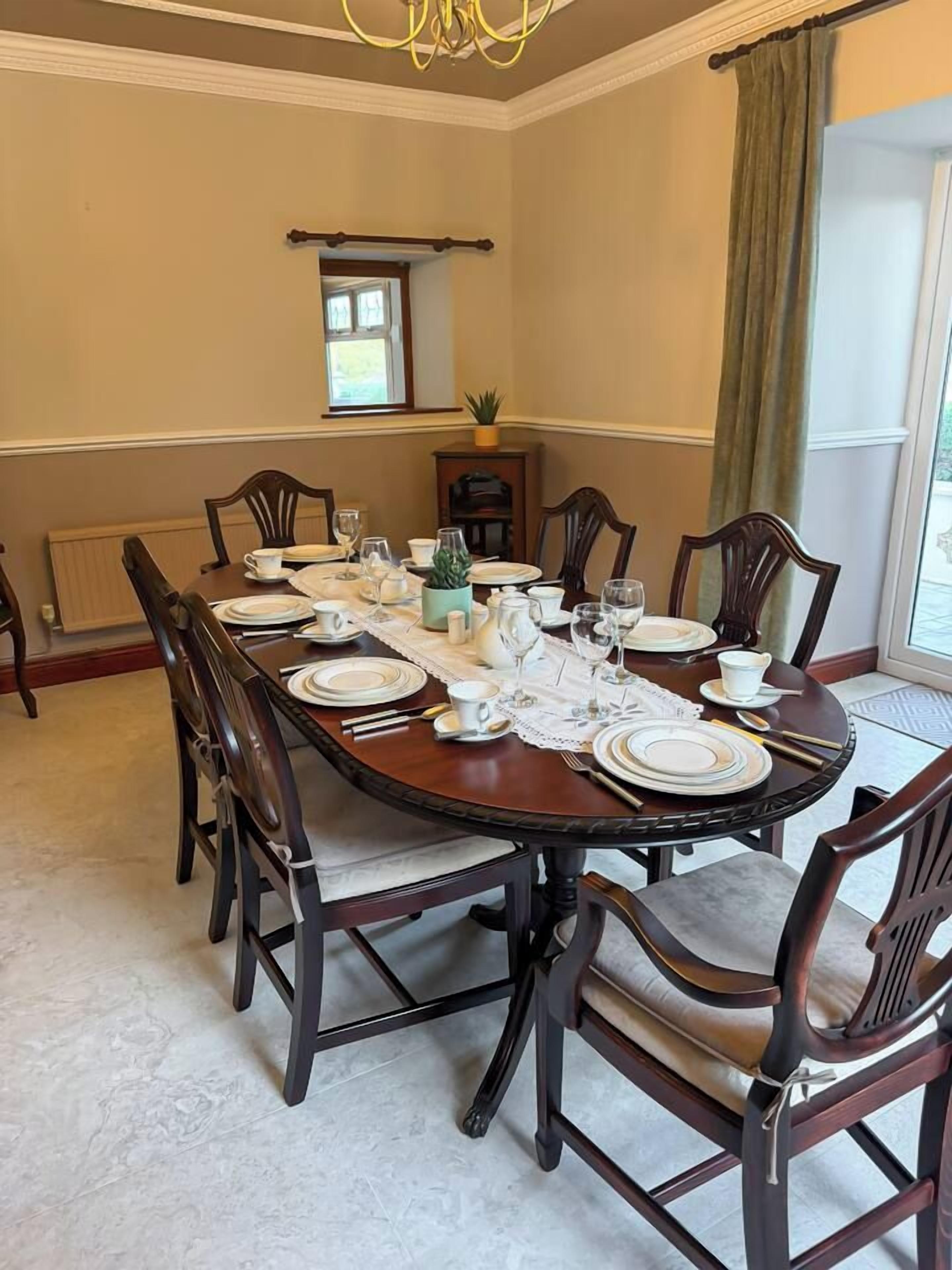 Une salle à manger avec une table ronde dressée pour six personnes, entourée de chaises en bois.