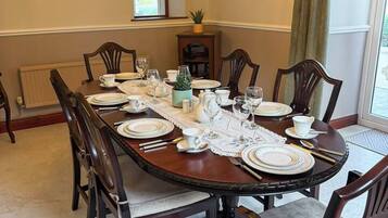 Une salle à manger avec une table ronde dressée pour six personnes, entourée de chaises en bois.