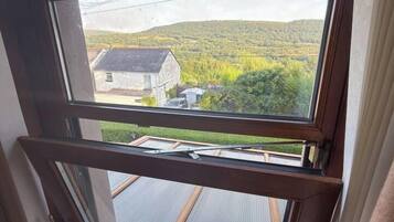 Une fenêtre donnant sur une maison et un paysage verdoyant.