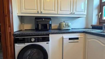 A compact kitchen with a washing machine, dishwasher, and a microwave on the countertop.