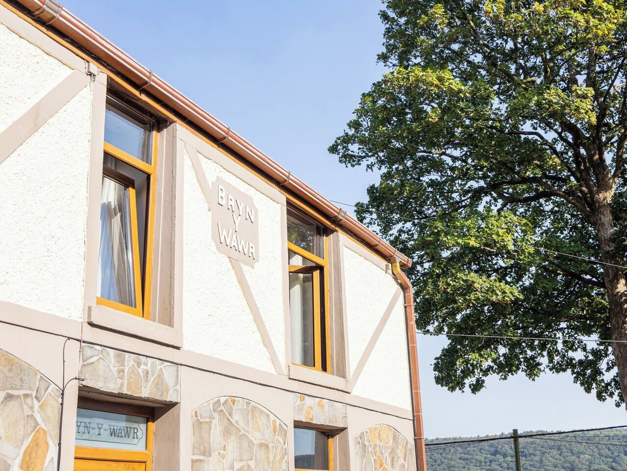 Ein Gebäude mit einem Schild, auf dem 'BYN Y WAWR' steht, und einer steinernen Fassade.