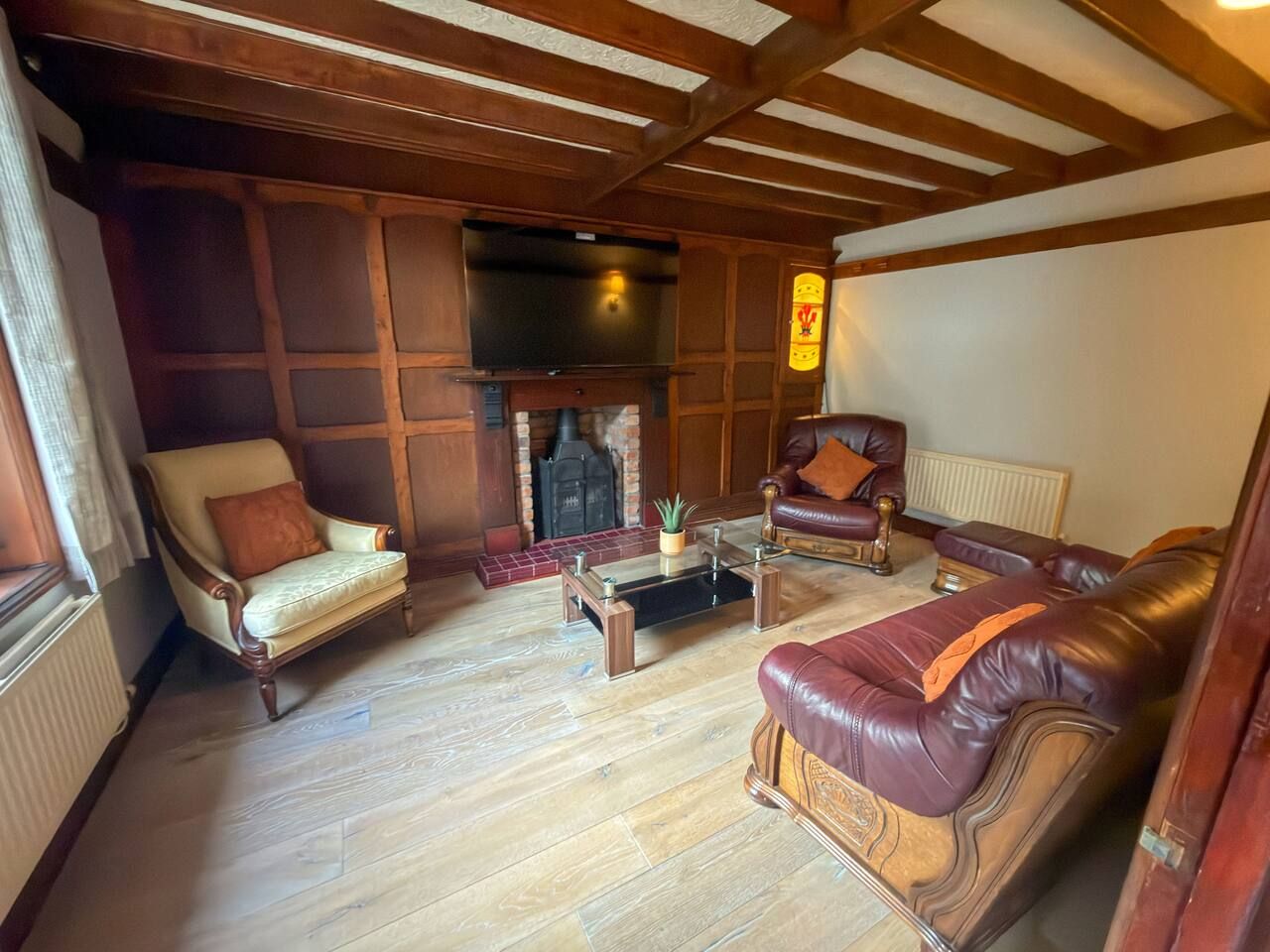 A traditional living room with a fireplace, leather sofas, and a wooden floor.