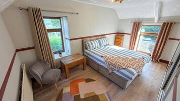 Ein Schlafzimmer mit Bett, Nachttisch, Stuhl, Fenster und Deckenleuchte.