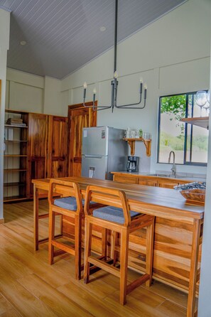 Une cuisine avec des meubles en bois, un réfrigérateur encastré, une machine à café et un coin repas avec des chaises en bois.