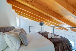 A bedroom with a sloped ceiling, a bed with pillows, a bedside table, and a fan. - Historic Palazzo Gritti - Lugano Lakefront Stay - Vaniglia, Morcote, Switzerland (Morcote)