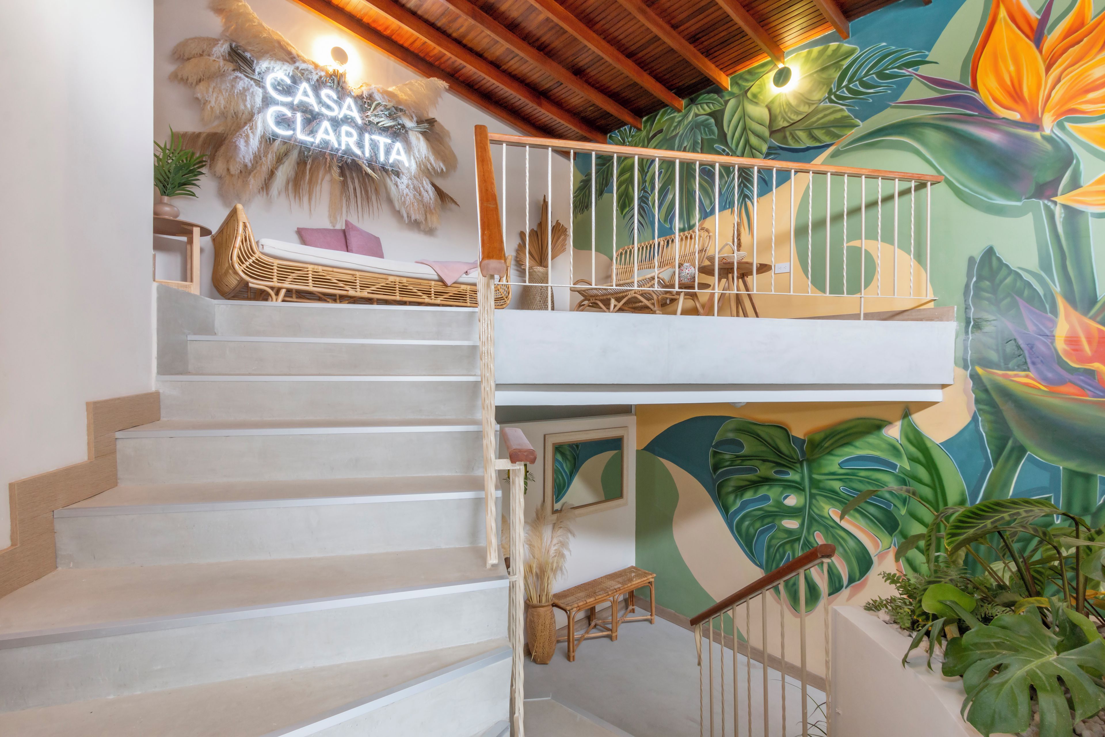 A staircase with a railing, a wall-mounted sign, and a mural with tropical foliage.