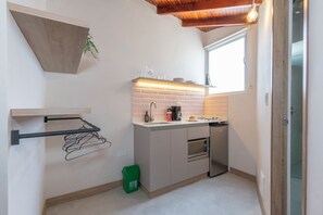 Una cocina compacta con horno integrado, cafetera y microondas.