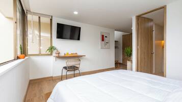 Een hotelkamer met een bed, een bureau, een stoel, een televisie en een deur.