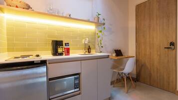 A compact kitchen with a built-in microwave, a coffee maker, and a small dining area with a chair.