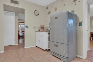 A kitchen with a large refrigerator, a coffee maker, and a clock on the wall. - Atomic Agave, Mid-Century Tucson Retreat (Tucson)