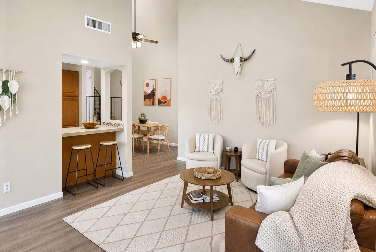 A modern living room with a sofa, coffee table, and a dining area with chairs and a table.