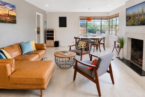 A modern living room with a sofa, chairs, a coffee table, a fireplace, and a large window with a view. - Cactus Comeback, A Retro Tucson Retreat (Tucson)