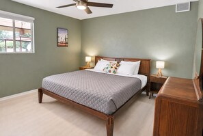 A bedroom with a bed, nightstands, a ceiling fan, a window, and a wall-mounted picture. - Cactus Comeback, A Retro Tucson Retreat (Tucson)