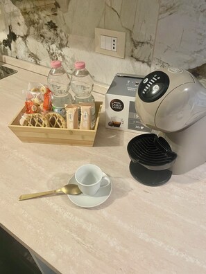 Eine Küchenarbeitsplatte mit einer Kaffeemaschine, einer Tasse, einem Löffel und einer Biscotti-Schachtel.