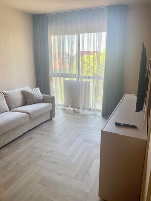 Ein modernes Wohnzimmer mit einer Couch, einem Flachbildfernseher und einem Parkettboden mit Zickzackmuster.