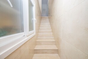 Eine enge Treppe mit einem Fenster links und einer Tür oben.