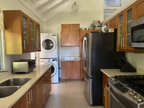 Eine kompakte Küche mit Waschmaschine, Kühlschrank, Herd und Holzausstattung.