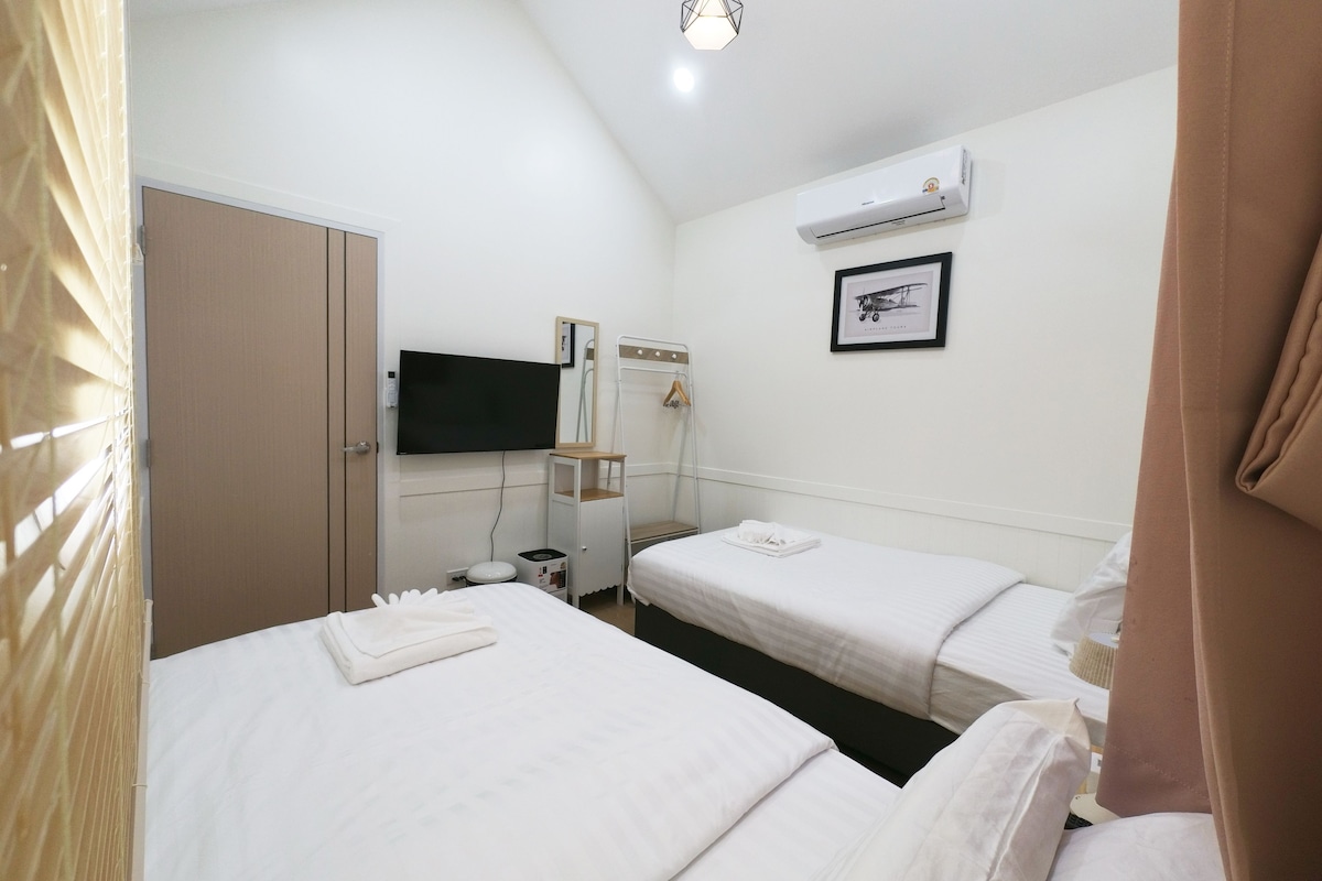 A hotel room with two beds, a flat-screen TV, an air conditioning unit, and a framed picture on the wall.