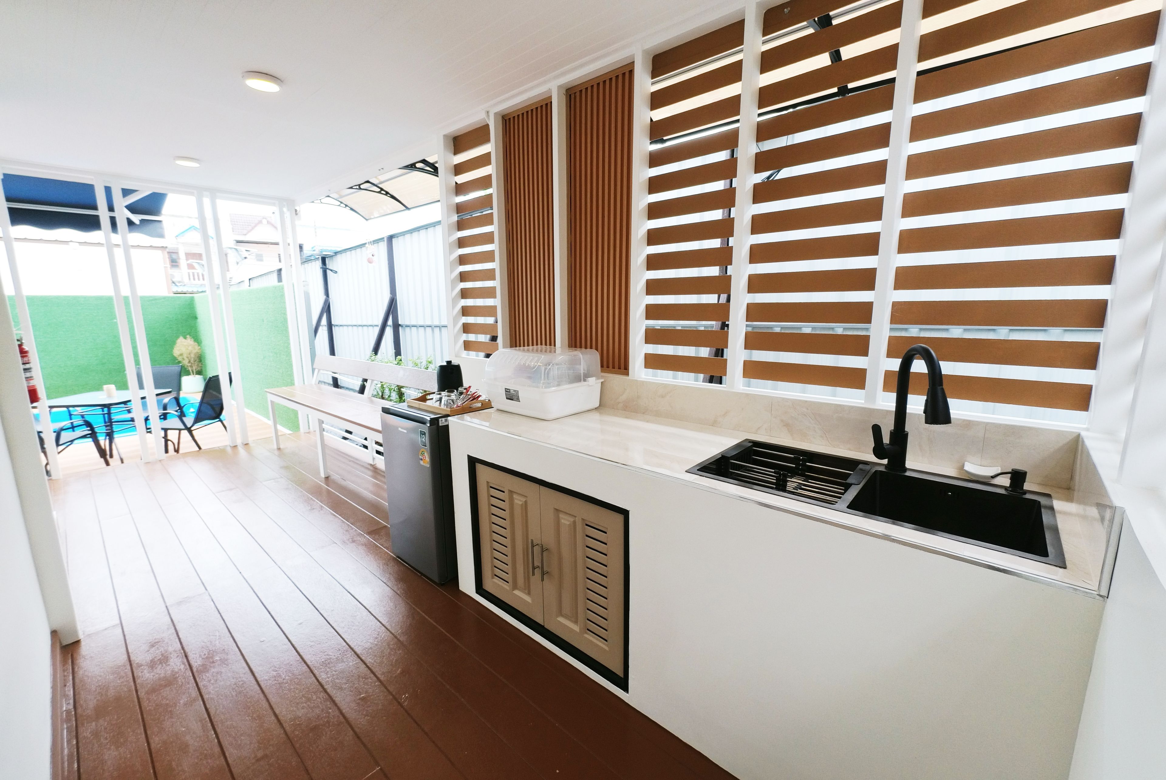 Una cocina compacta con pileta integrada, un refrigerador pequeño y una ventana con persianas.