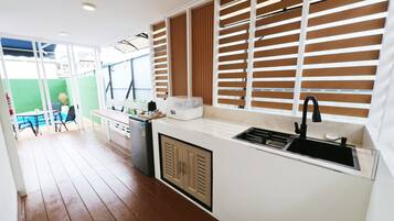 Una cocina compacta con pileta integrada, un refrigerador pequeño y una ventana con persianas.