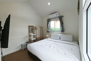 A bedroom with a bed, a mirror, a wardrobe, a small bedside table, and an air conditioning unit. - 49 Pool Villa Bangsaen (Mueang Chonburi)