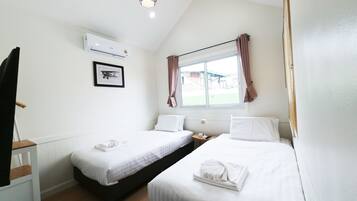 Habitación de hotel con dos camas, una ventana con cortinas, un cuadro en la pared y un equipo de aire acondicionado.