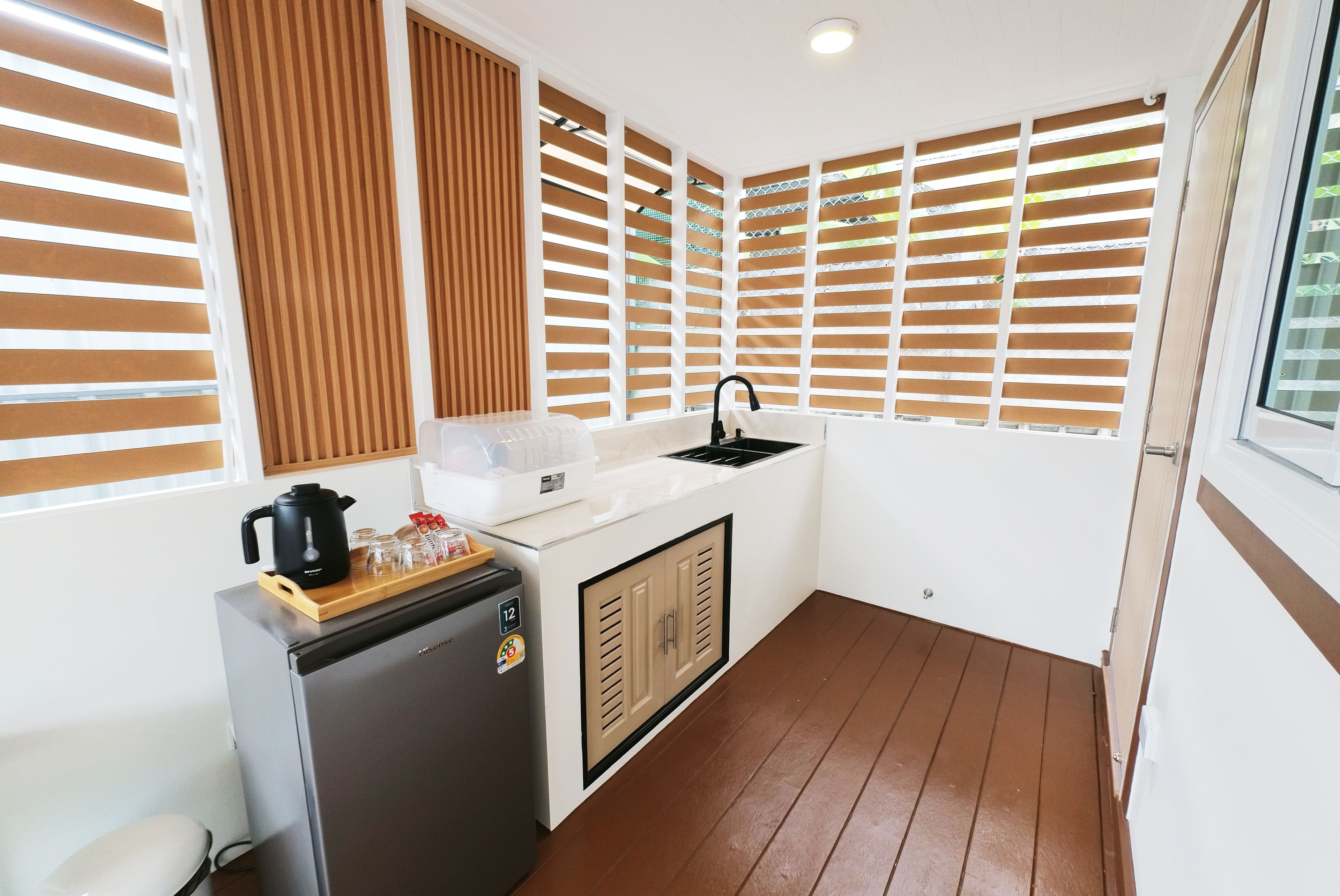 A compact kitchenette with a refrigerator, a coffee maker, and a sink.