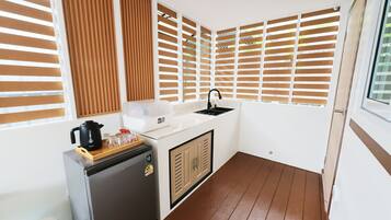 A compact kitchenette with a refrigerator, a coffee maker, and a sink.