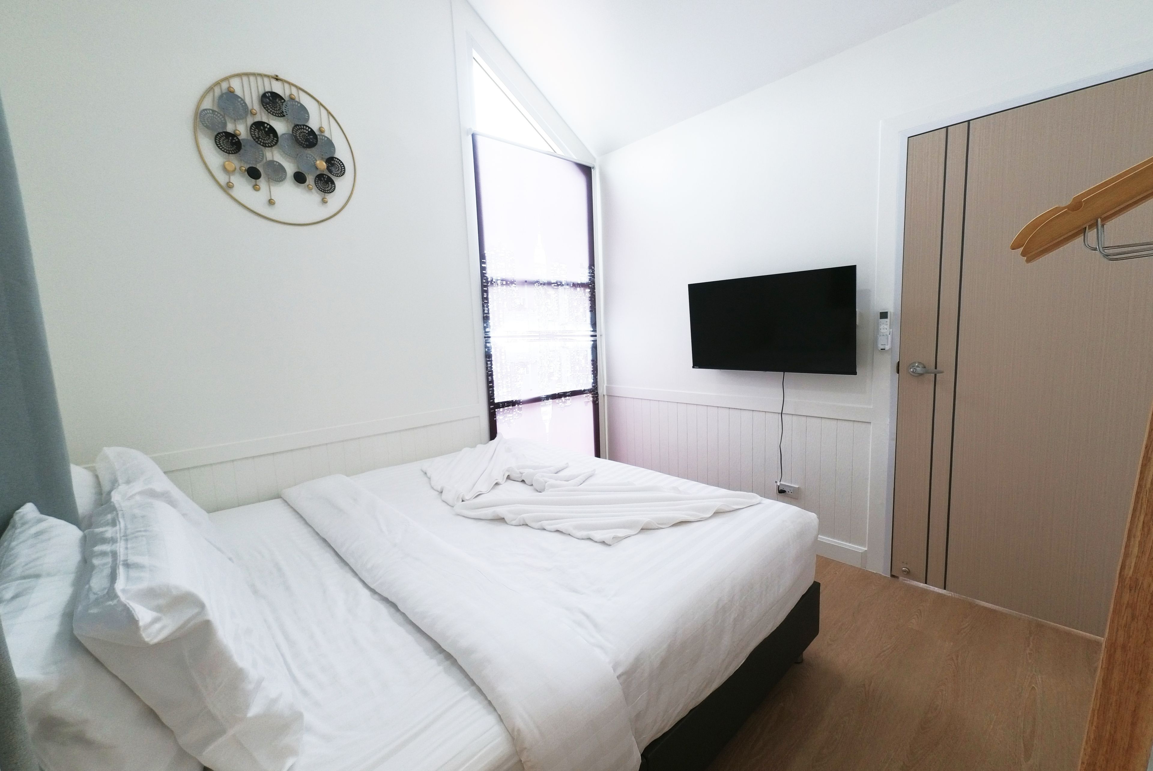 Una camera da letto con un letto, una televisione a parete e un armadio.