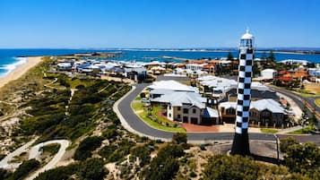 A coastal residential area with a lighthouse, houses, and a beach.